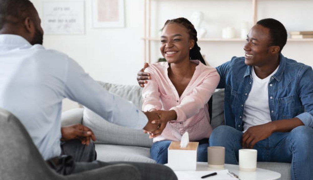 Successful Marital Therapy. Happy Black Spouses Handshaking With Family Counselor After Reconciliation, Thankful For Professional Help And Saved Marriage, Sittion On Couch In Office, Free Space